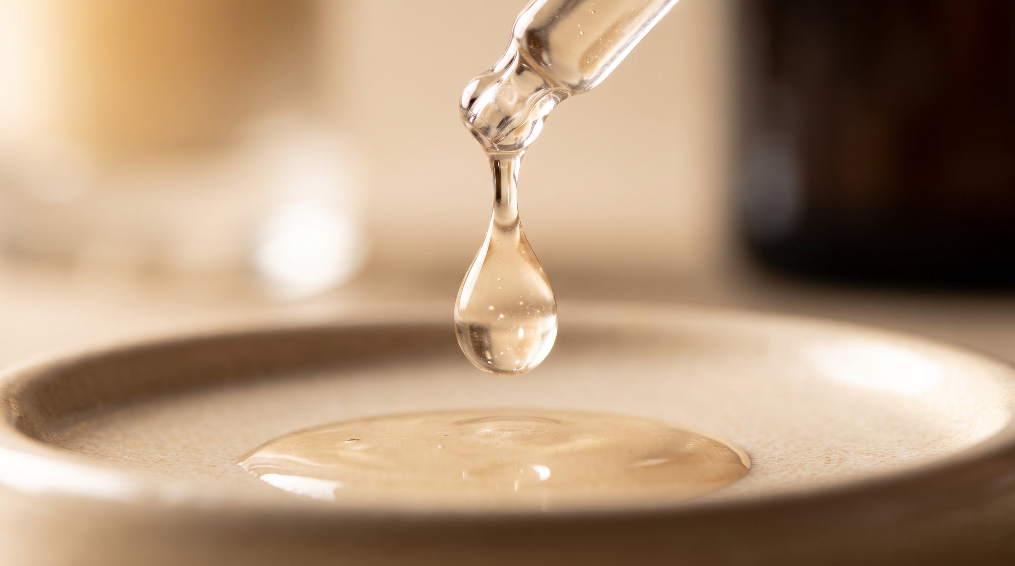 Macro shot of a clear serum droplet falling from a glass dropper